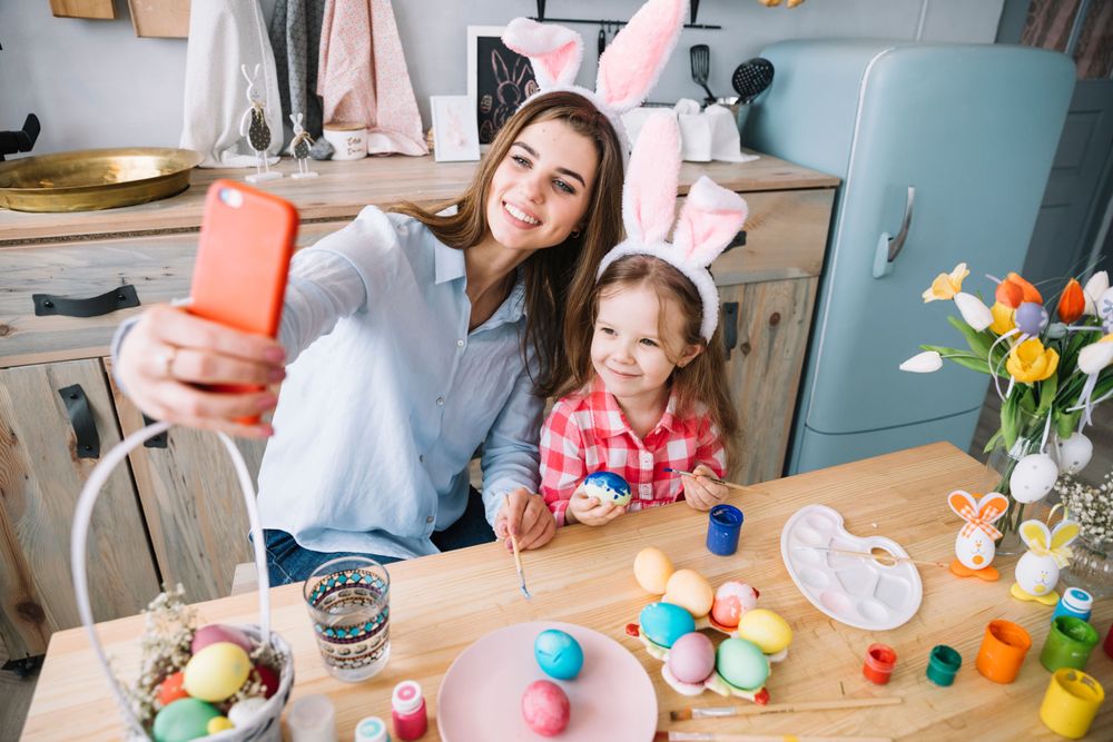 young-woman-taking-selfie-with-daughter-near-easter-eggs.jpg